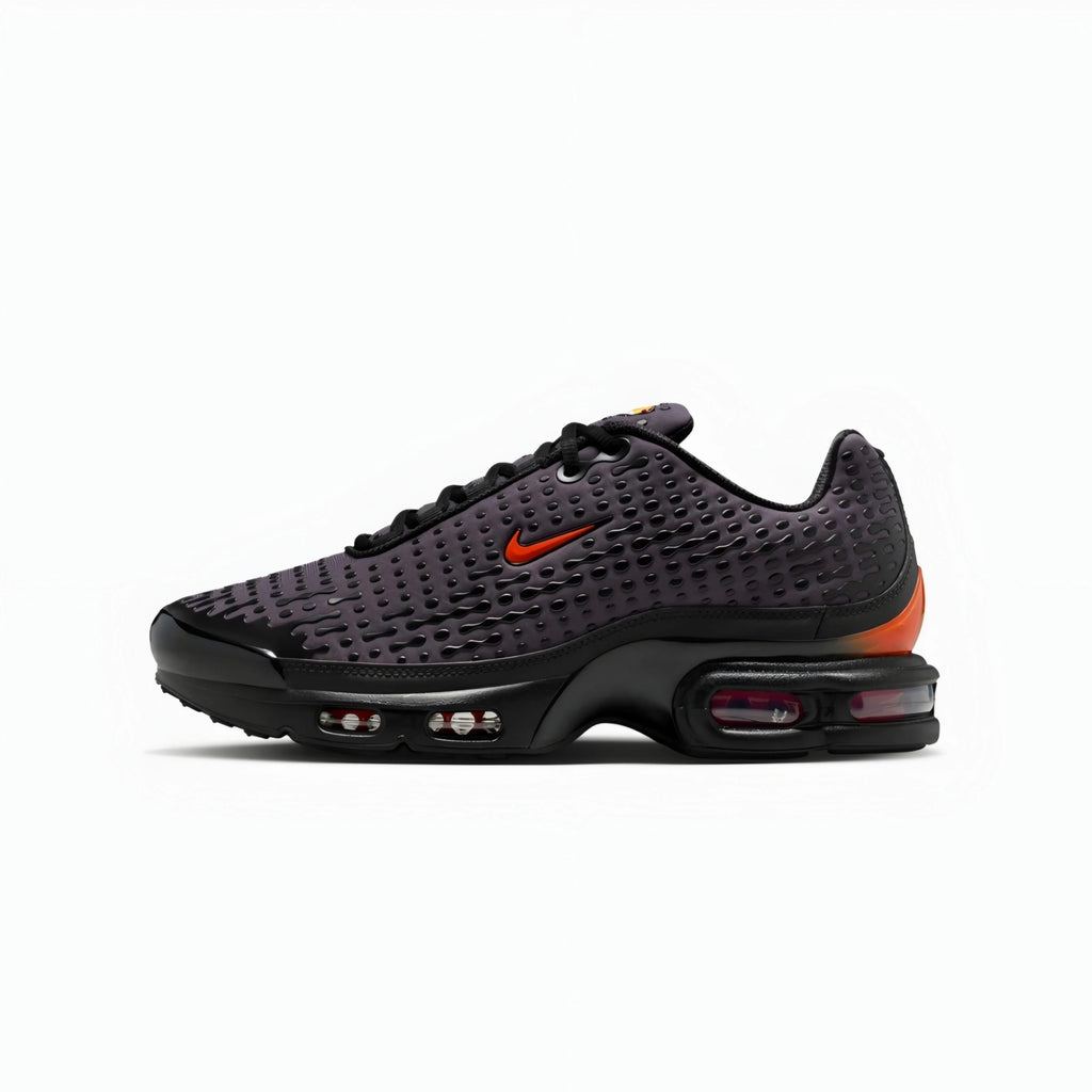 A Nike Air Max Plus sneaker in black with a textured knit upper, a bright orange Nike Swoosh, and an orange heel accent, shown against a plain white background.