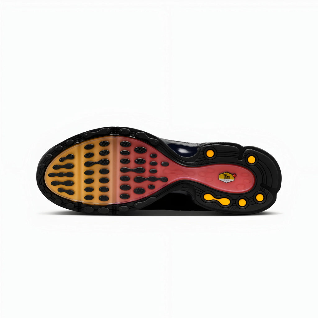 The outsole of a sneaker shown from a top-down view, featuring a black rubber base with a translucent gradient midsole shifting from yellow to red, and small yellow accents.