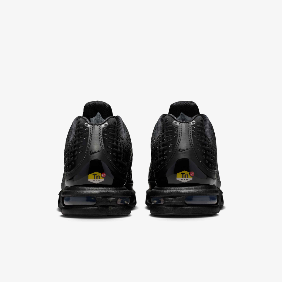 A pair of black Nike Air Max 90 sneakers shown from the back, featuring a small yellow and red 'THC' logo on the heel counter, set against a plain light gray background.