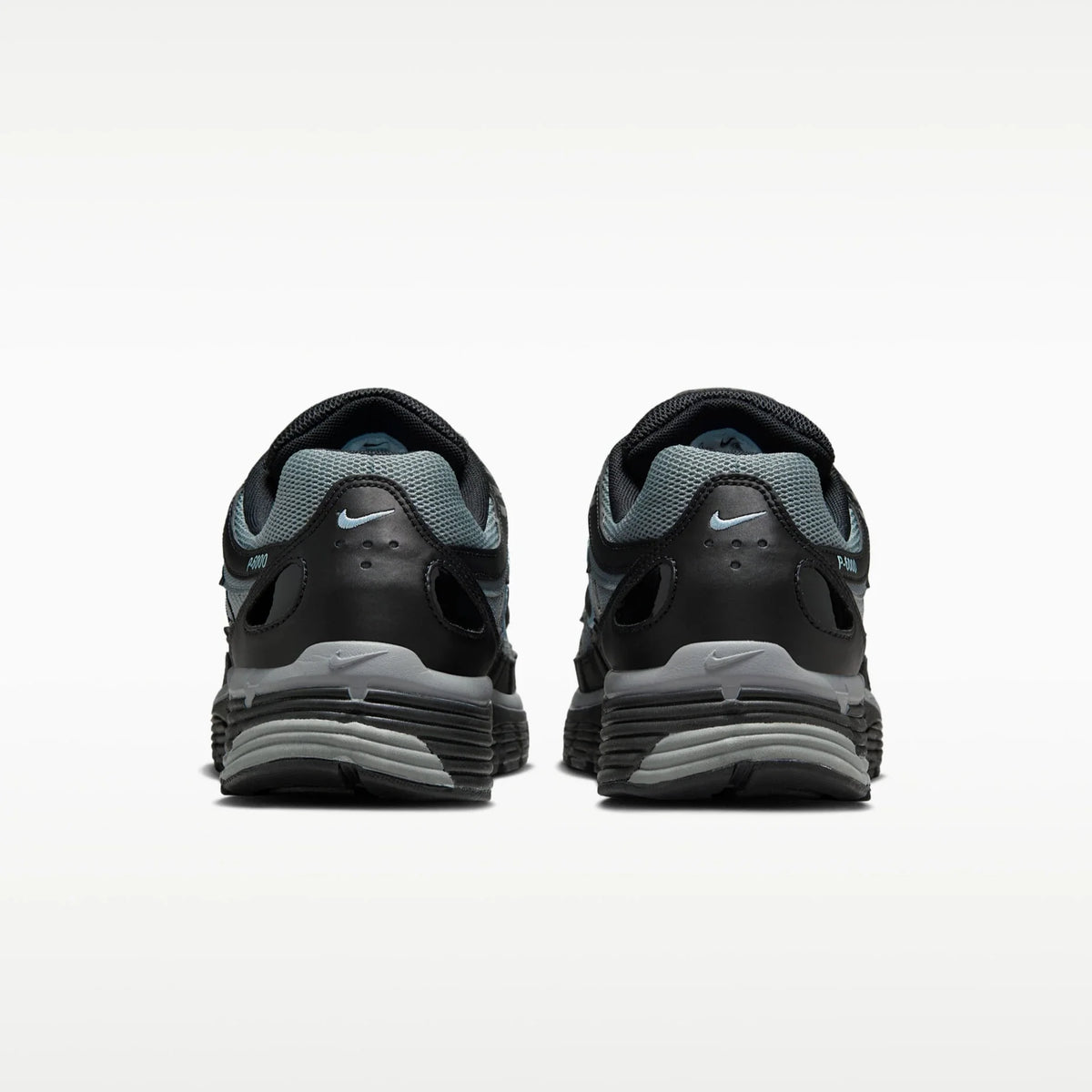 A pair of Nike P6000 running shoes shown from the rear, featuring a black and gray design with a light blue Nike Swoosh on the heel and tongue.