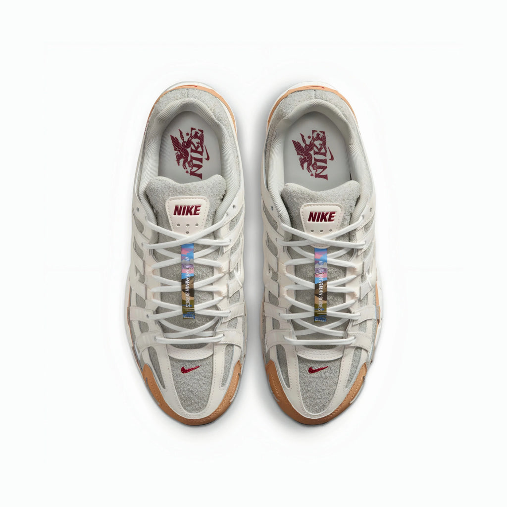 A pair of Nike P6000 sneakers shown from a top-down view on a clean white background. The shoes feature a light gray and white mesh and suede upper, white laces, a translucent gum outsole, and a red Nike Swoosh on the toe box.