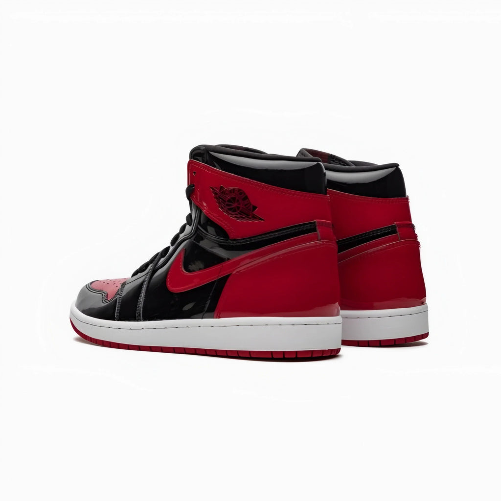 A pair of Jordan 1 high-top sneakers in red and black with a white midsole, shown from a side-rear angle on a clean white background.